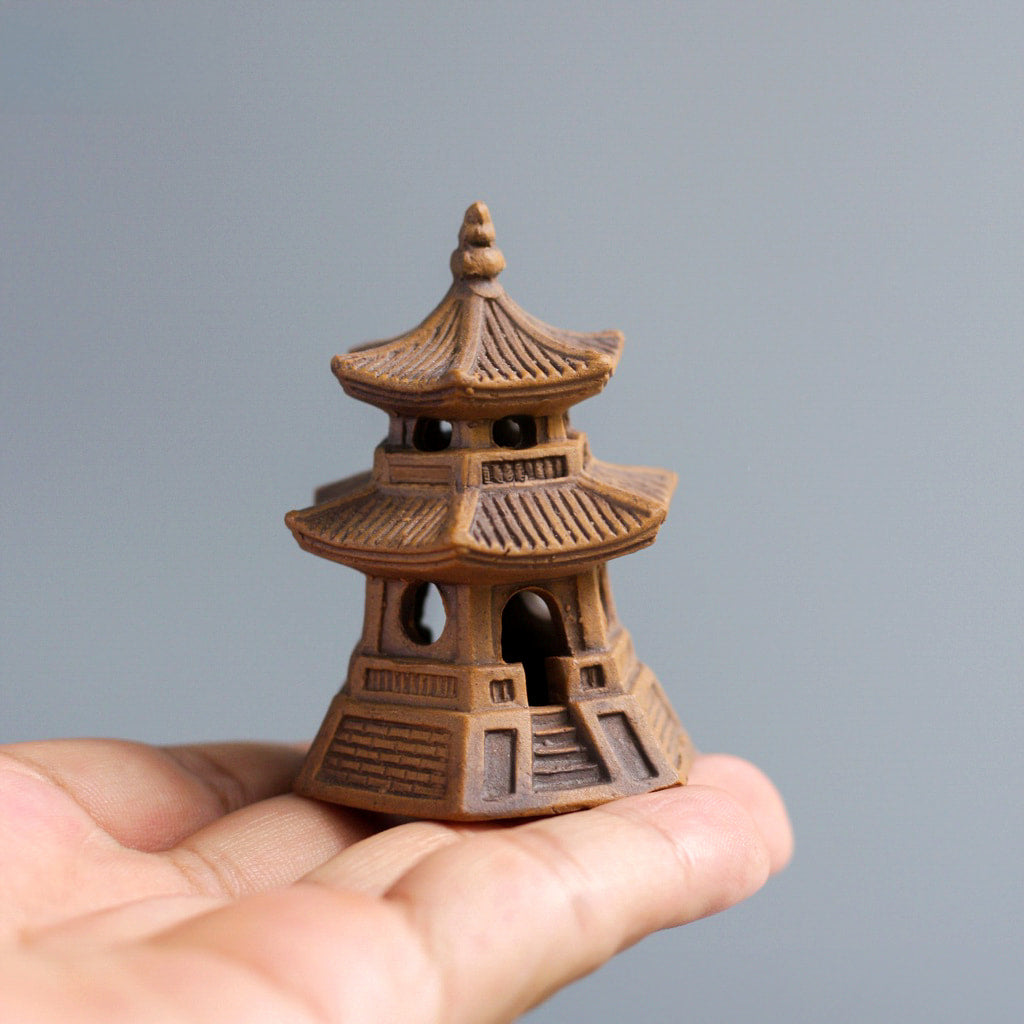  The small, round miniature Japanese pagoda for bonsai is held in a person's palm to show its compact size and detailed design.