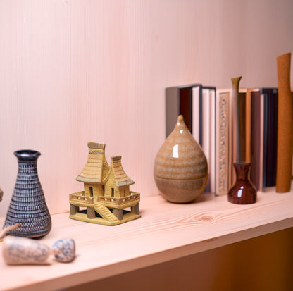 : Adding a touch of cultural charm to a modern bookshelf, this hand-painted ceramic stilt house, with its earthy tones and intricate details, embodies the warmth and craftsmanship of Vietnamese artistry.