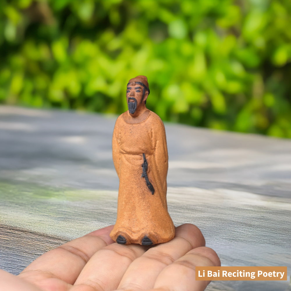  A small, unglazed, brown ceramic figure of Li Bai, a famous Chinese poet, standing on a person's fingertip. He is wearing a long robe and has a sword at his waist.