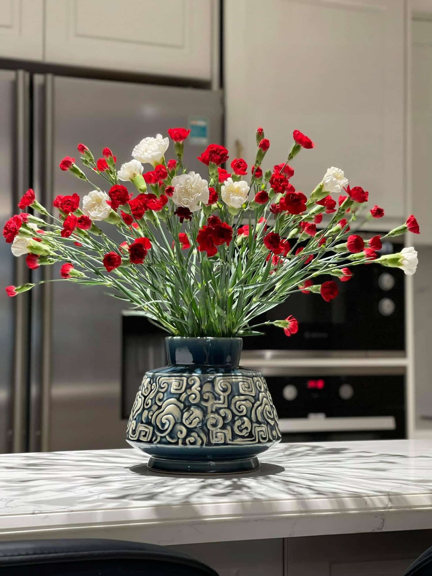This low wide flower vase, an artisan vase for a kitchen island, holds red & white flowers.