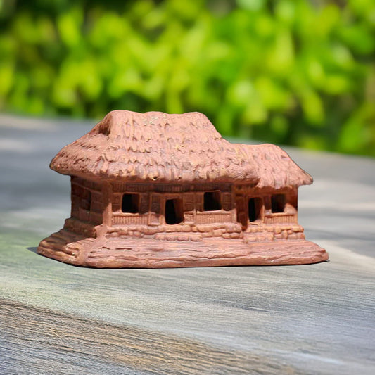  A small clay figurine of a house with a thatched roof, showcasing intricate details and a rustic design.