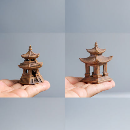 Two ceramic miniature japanese pagoda held in hands against a gray background