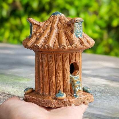 : A delicate, hand-painted treehouse, crafted in the heart of Bat Trang village, rests gently in a hand, showcasing its miniature size and intricate artistry.