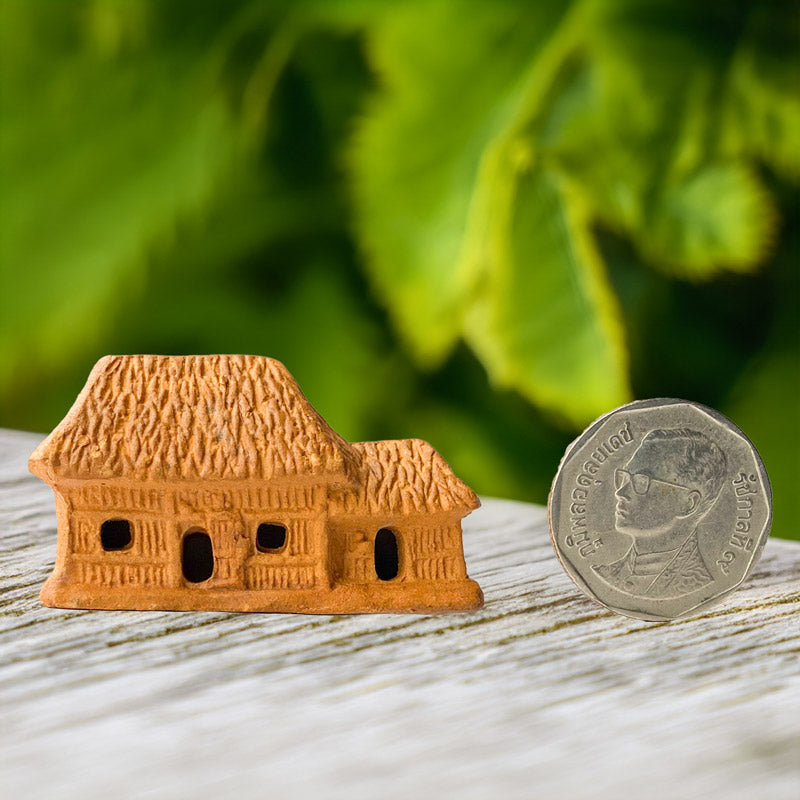 This tiny ceramic house, handcrafted with intricate detail, sits beside a coin, showcasing its miniature size and making it the perfect accent for bonsai trees and terrariums.