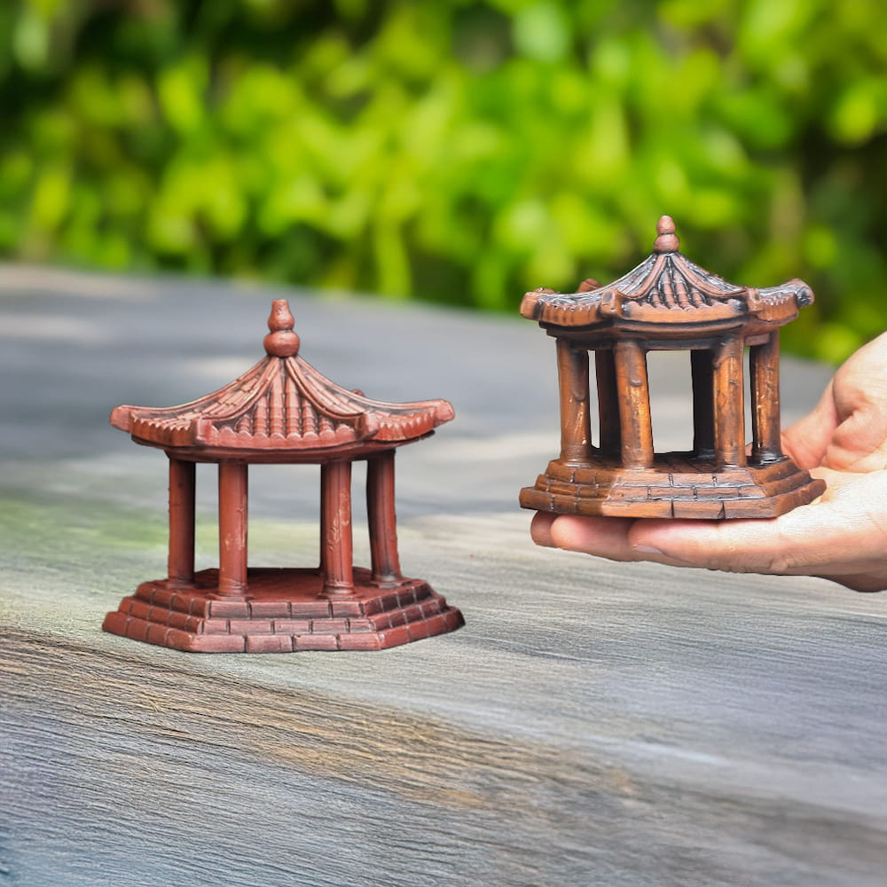 Two small brown ceramic pavilions held in a hand.