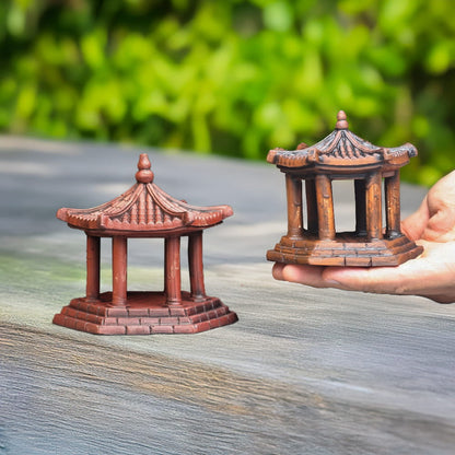 Two small brown ceramic pavilions held in a hand.