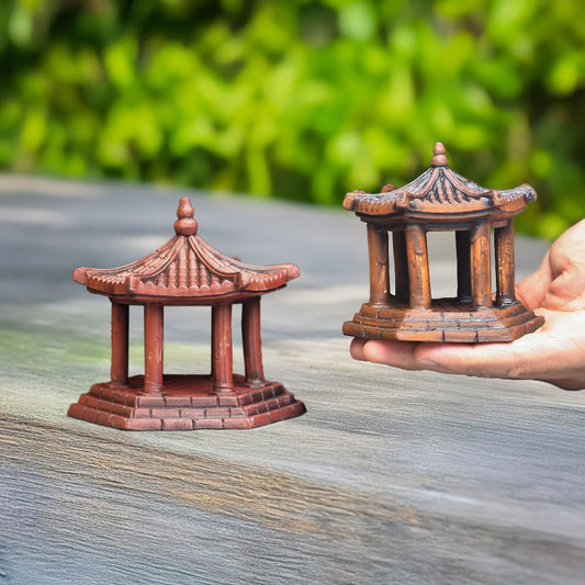 Two small brown ceramic pavilions held in a hand.