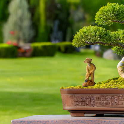 A miniature ceramic figurine gardener, meticulously crafted from Vietnamese ceramic, brings life and purpose to a majestic bonsai tree, creating a miniature world of serenity and harmony.