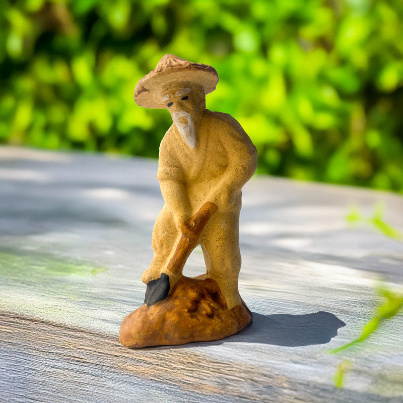  A miniature gardener, handcrafted from rustic Bat Trang ceramic, diligently tends to his miniature garden with a small hoe, adding a touch of serenity and diligence to your bonsai.