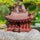 Large pagoda statue for bonsai on rock. Tiny robed bonsai figurine beside this Zen garden decor.