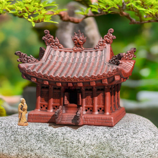Miniature pagoda for bonsai on rock. Tiny robed bonsai figurine beside this Zen garden decor.