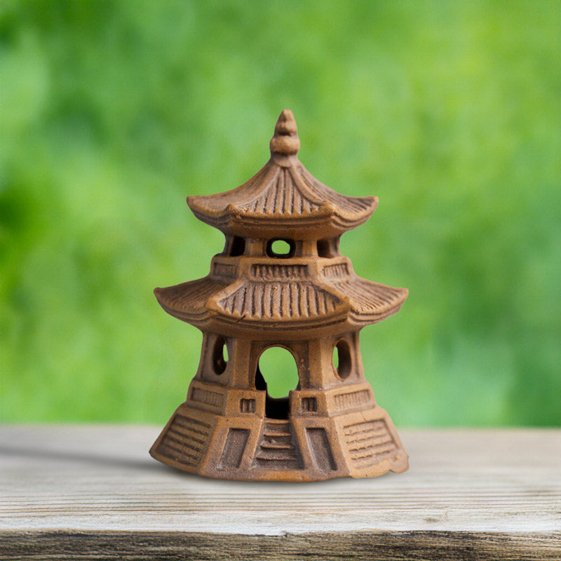 Small Round Ceramic Jpanese pagoda figurine on a wooden surface with a blurred green background