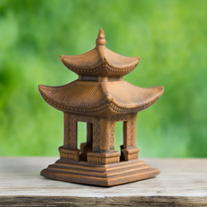 Ceramic japanese pagoda figurine on a wooden surface with a blurred green background