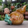 A close-up of a unique bonsai pot. A small monk figure makes this a charming bonsai statue pot.