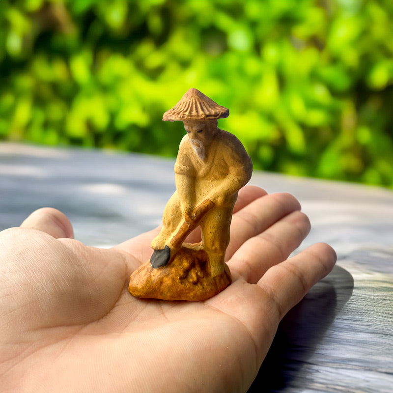 This tiny mudman figurine, handcrafted with intricate detail, depicts a hardworking gardener diligently tending his miniature plot, perfect for adding a touch of rustic charm to your bonsai.