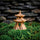 An ornate three-tier ceramic pagoda figurine with a circular base, nestled in green moss. This piece of Japanese decor is fired at high temperatures for lasting durability in terrariums or bonsai displays.