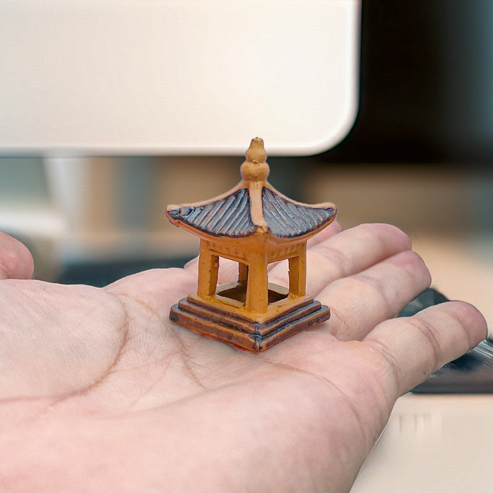 A hand holding the taller miniature pagoda to demonstrate its small size, suitable as bonsai figurines or ceramic aquarium decor.