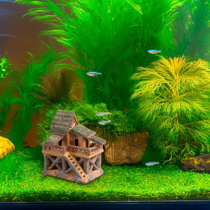 Nestled amongst vibrant aquatic plants, a miniature ceramic treehouse provides a safe and charming haven for fish and other aquatic creatures, creating a miniature oasis in your aquarium.