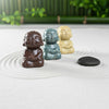 Three small buddha statues in brown, blue, and cream. A buddha figurine set for a zen garden