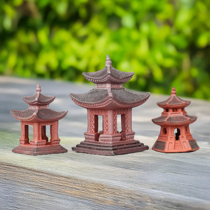 Three red Japanese pagodas of different sizes stand on a wooden table. Each pagoda features a unique design, offering a variety of styles for miniature gardens and bonsai displays.