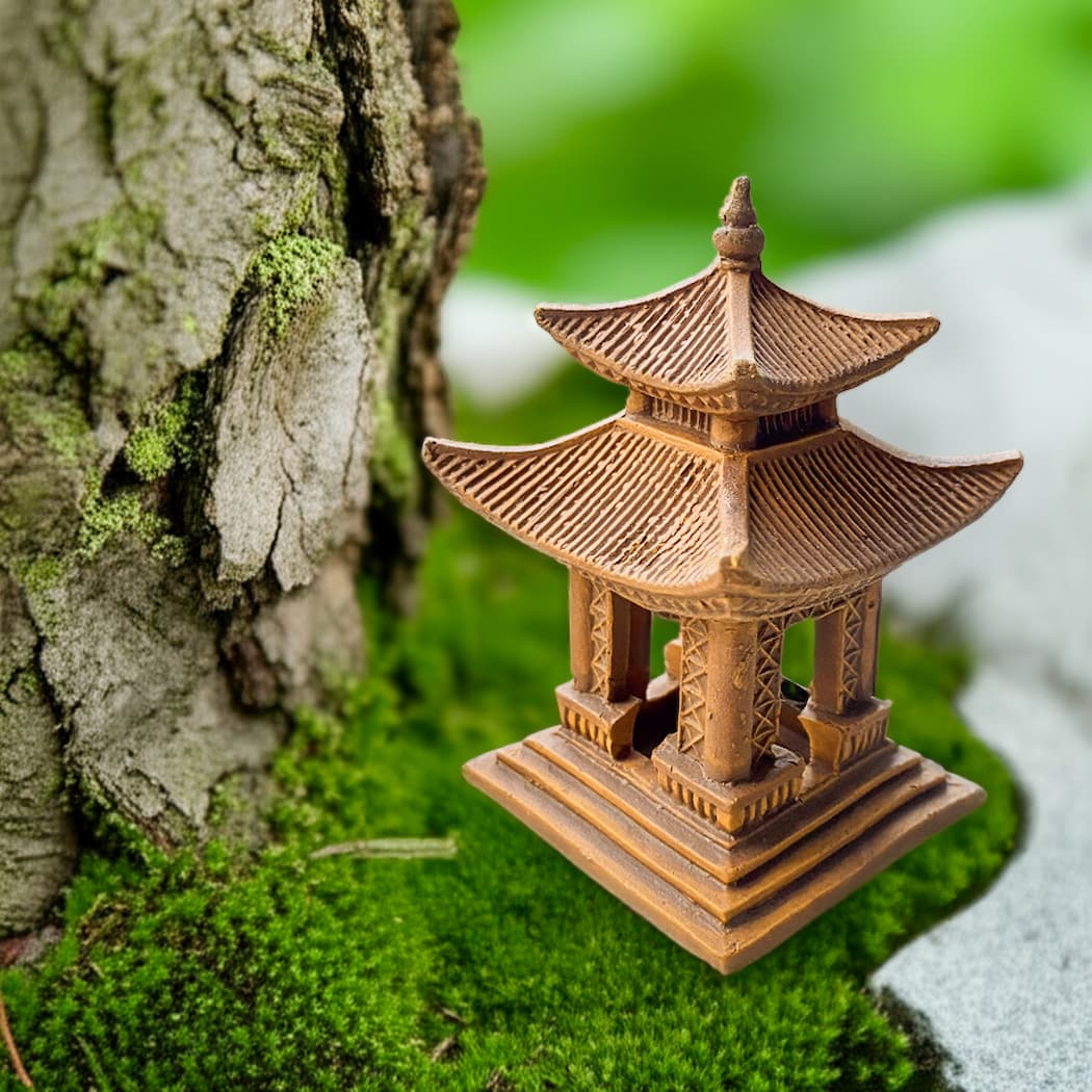 One brown miniature Japanese pagoda beside tree trunk; a ceramic pagoda for bonsai accent.