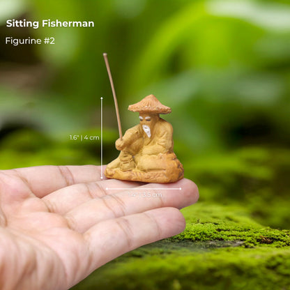 A tiny Sitting Fisherman bonsai mudmen figure in hand. It's a detailed bonsai figurine.