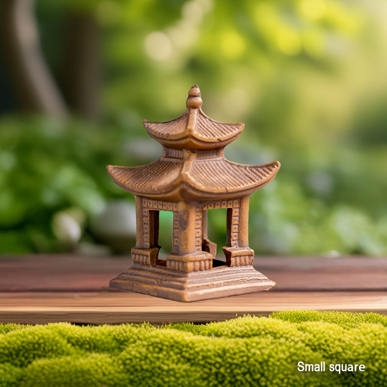  A small square brown clay pagoda statue is placed on a wooden surface with green moss. This ceramic pagoda is a good size for bonsai pagoda accessories.