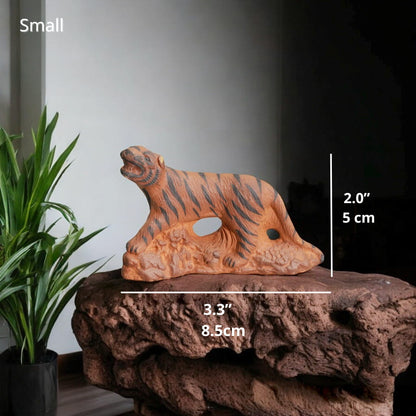 Small Ceramic Tiger Figurine on rock. Tiger miniature for bonsai decor. Plant background.