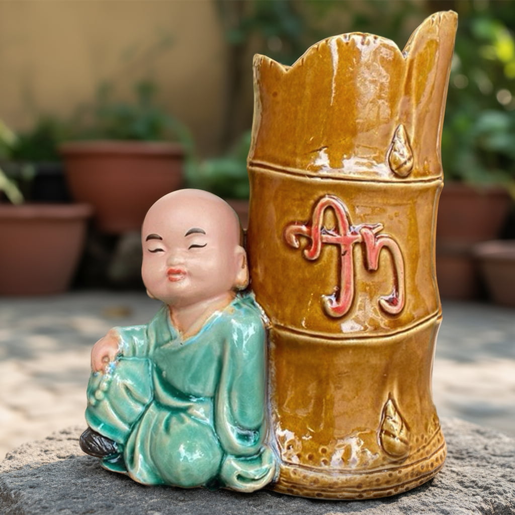Close-up of the statue bonsai planter. Shows the glossy brown glaze and the monk's calm face.
