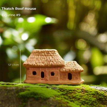  A small thatch roof house bonsai figurine sitting on moss. A rustic piece of bonsai decor.