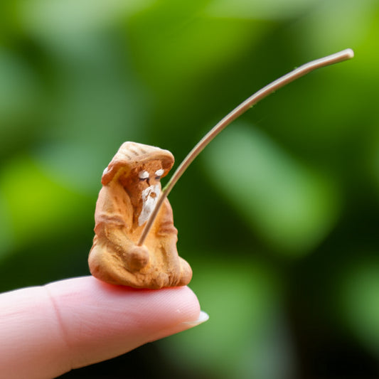  A very tiny miniature fisherman figurine with a rod, sitting on a fingertip.