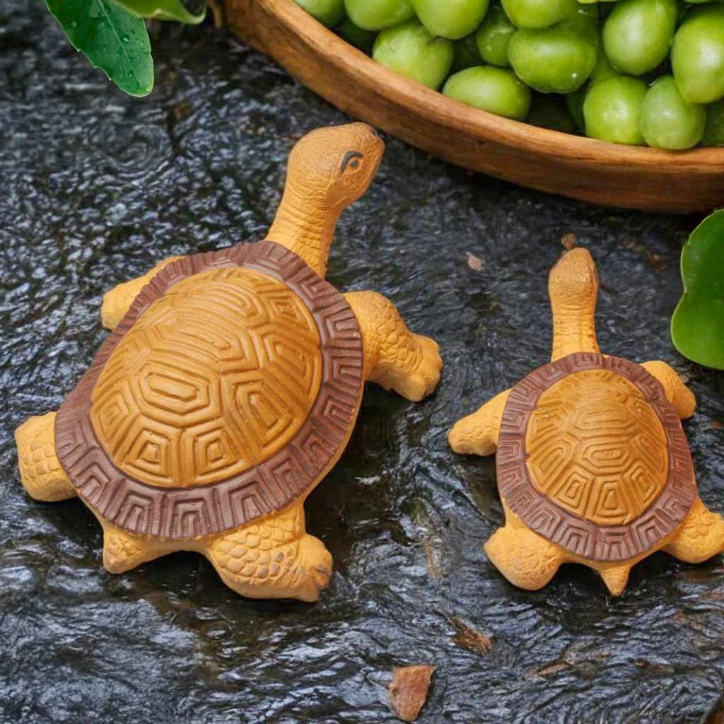 Two turtle tank decor pieces: a ceramic turtle figurine and a large turtle statue, near green plants.