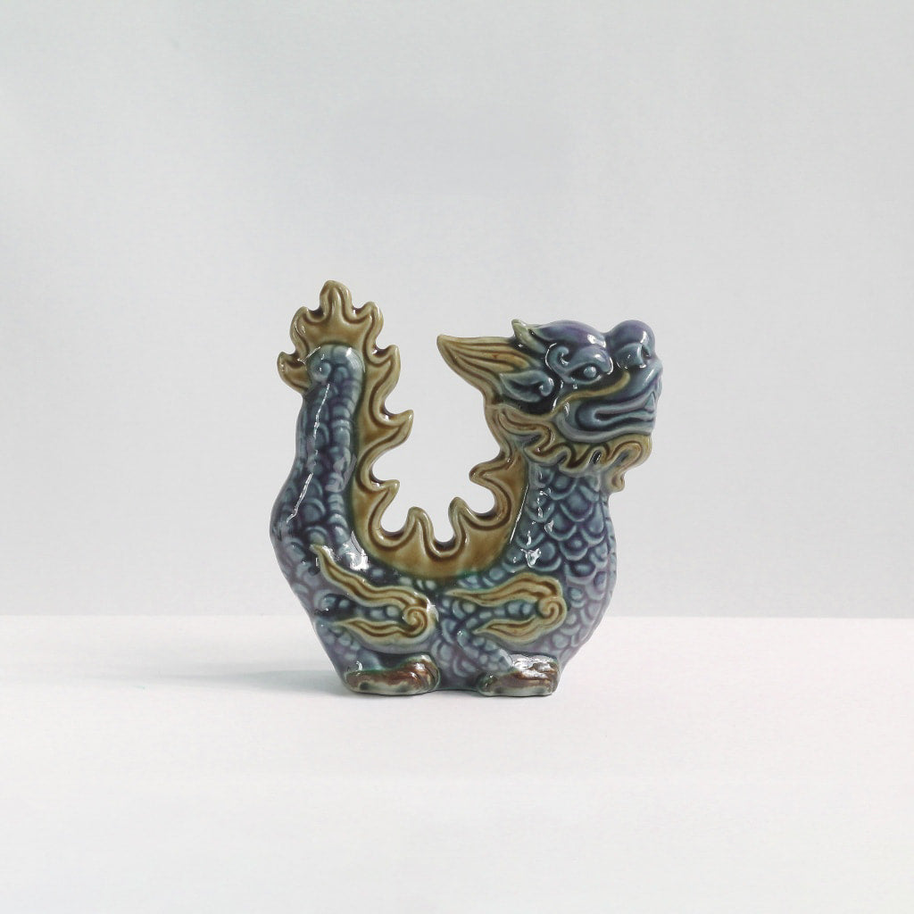 Side view of a blue-glazed handmade ceramic dragon. A unique office desk dragon figurine.