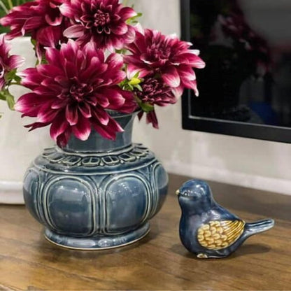 A blue Vietnamese ceramic vase holding purple flowers, styled next to a small ceramic bird figurine.