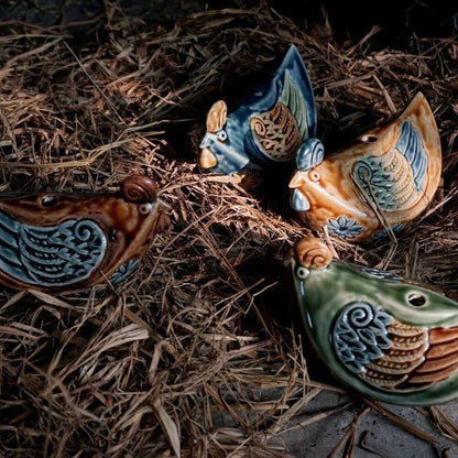 Four colorful Vietnamese folk art chicken figurines on straw, a classic Vietnamese pottery rooster style.