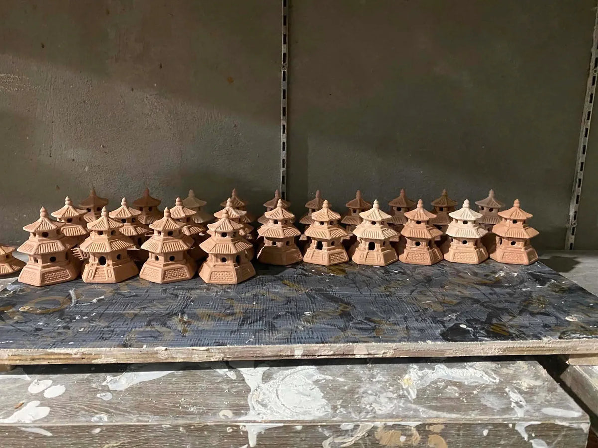 A finished batch of handmade ceramic pagoda pieces drying on a workshop shelf at Duc Huy Pottery, an example of a past custom order.