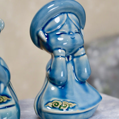 Blue-glazed seated Vietnamese girl figurine with traditional round hat