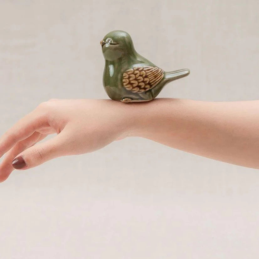 Green-glazed Vietnamese ceramic bird figurine resting on a hand for scale