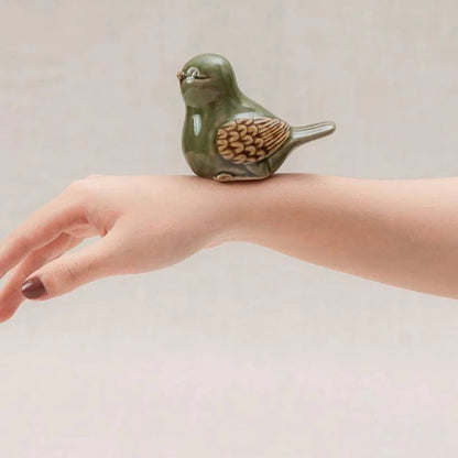Green-glazed Vietnamese ceramic bird figurine resting on a hand for scale